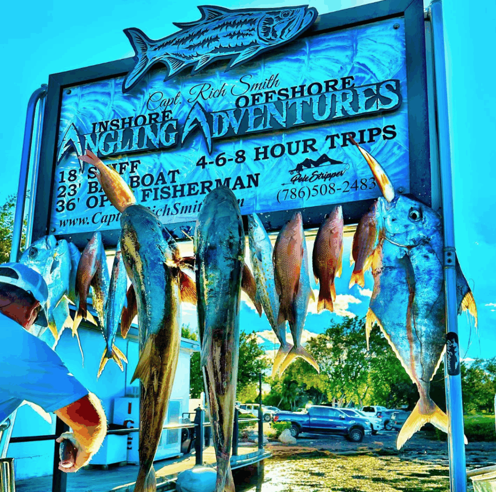Sign displaying various caught fish including snapper and mackerel, promoting Capt. Rich Smith's Angling Adventures for fishing trips in the Gulf of Mexico.