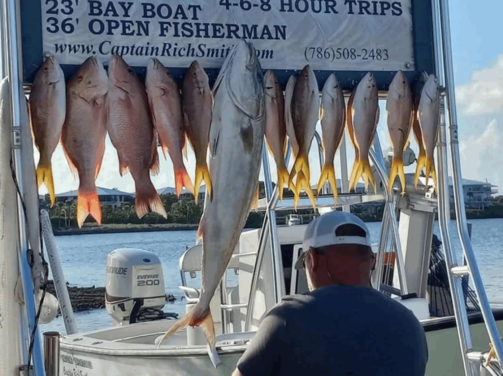 Man observing a catch of Mutton Snappers displayed on a fishing charter boat in the Florida Keys, showcasing successful fishing trip results.