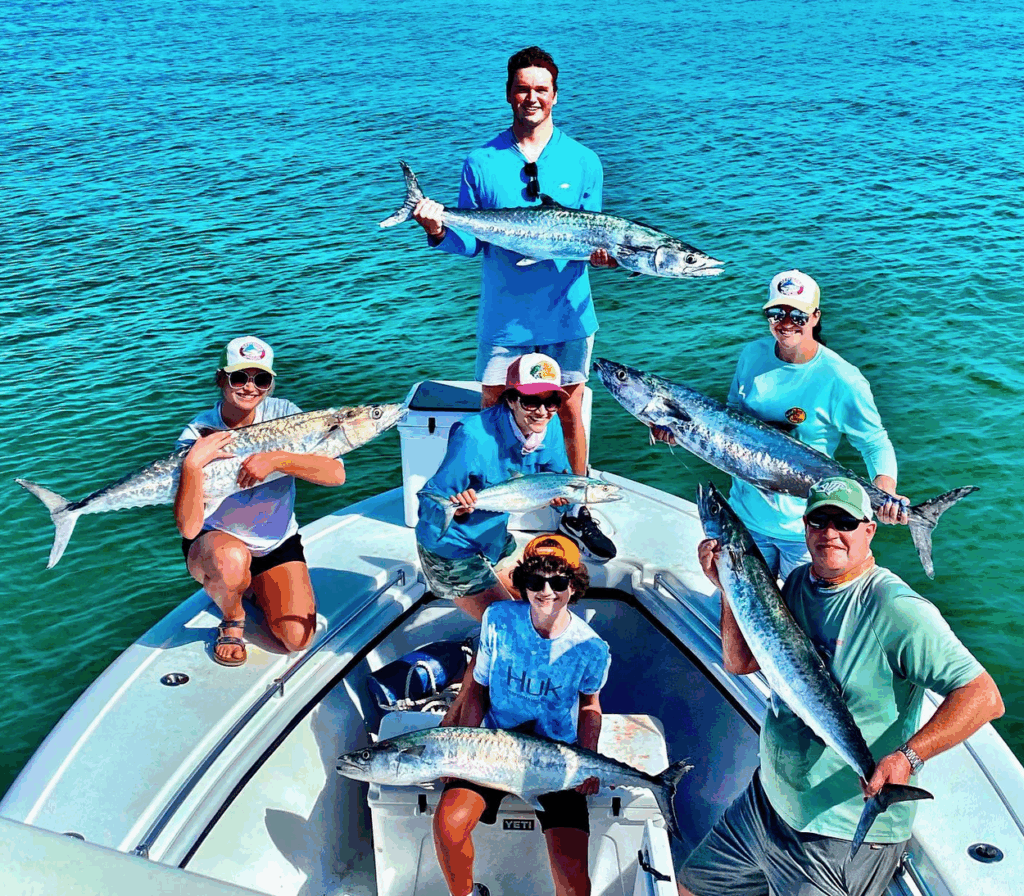 Group of anglers on a boat holding large fish, showcasing a successful wreck fishing trip in the Florida Keys.