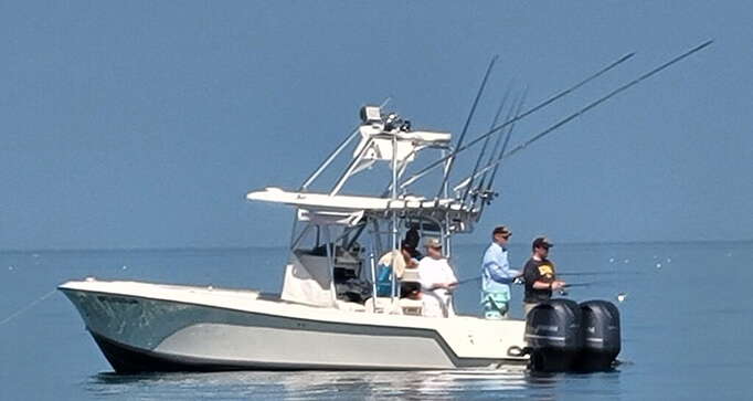31′ Center Console fishing boat with four anglers, fishing rods, and calm waters in the Florida Keys.