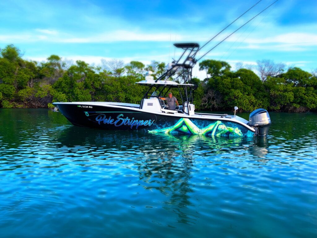 36-foot center console fishing boat named "Pole Stripper," featuring vibrant graphics, anchored in calm waters surrounded by mangroves, with a captain at the helm, ideal for fishing charters in the Florida Keys.