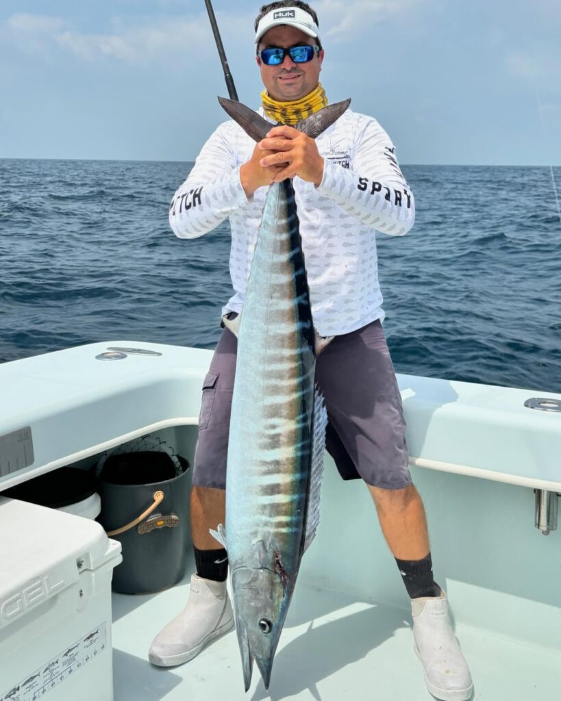 Captain holding a large fish on a fishing charter in the Florida Keys, showcasing a successful catch with ocean backdrop.