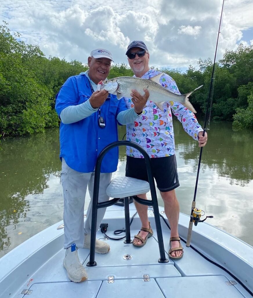 Two fishermen on a boat in the Florida Keys, one holding a fish, showcasing a successful catch during a fishing charter experience.