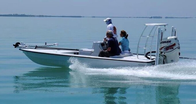 18-foot flats skiff with three passengers, cruising through calm waters in the Florida Keys, ideal for fishing charters.