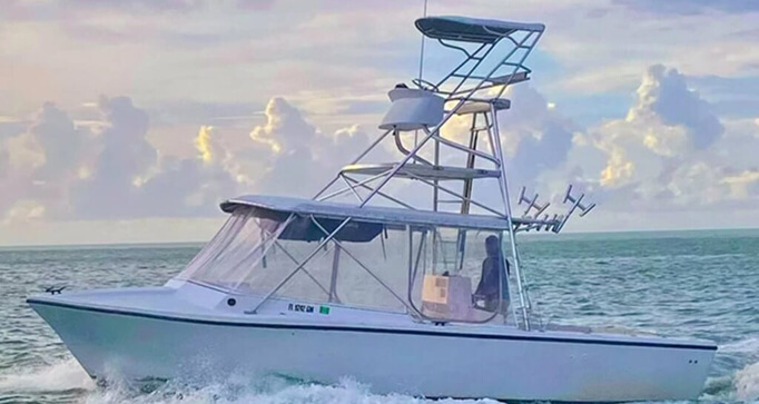 30′ sport fishing boat cruising in the Florida Keys, equipped with fishing rods and a spacious cabin, showcasing vibrant sky and ocean backdrop.
