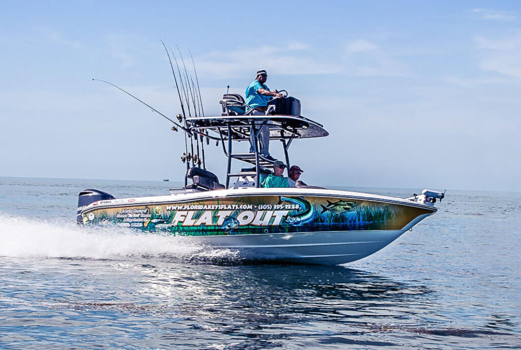 24′ hybrid bay boat in motion on clear waters, featuring fishing gear and four anglers, designed for versatile inshore fishing in the Florida Keys.