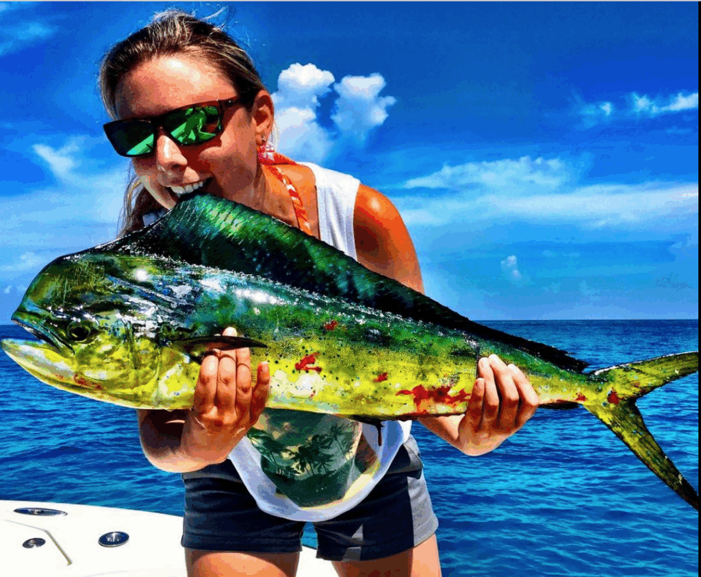 Woman holding a vibrant Mahi Mahi fish while offshore fishing in the Florida Keys, showcasing the colorful scales and clear blue water background.